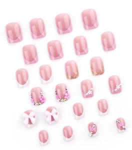 Close-up of pink press-on nails with 3D floral accents, rhinestones and white bows