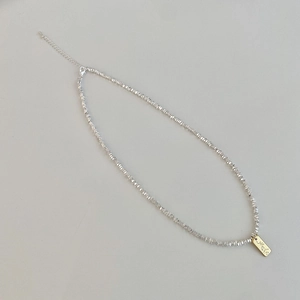 Detail of silver irregular bead chain with a gold handmade pendant and lobster clasp