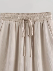 Détail du pantalon plissé abricot montrant la taille élastique et la texture verticale