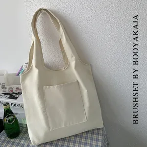 Detail of off-white canvas tote bag with front pocket in a lifestyle setting