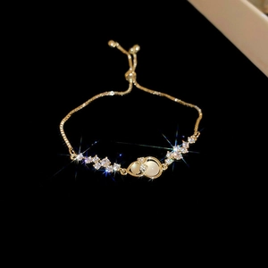 Detail view of gold sliding bracelet with zircon accents and white opal stone