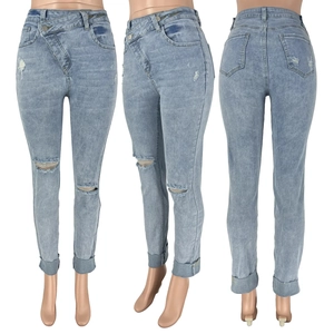 Detail view of light blue ripped jeans showing asymmetric cross waist and distressed knees