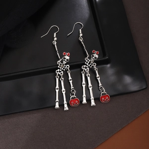 Detail of Halloween skeleton earrings with red bow accent and a smiling round pendant