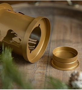 Close-up of golden metal lantern with hollow deer pattern on a wooden surface
