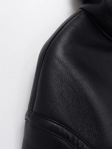 Close-up macro detail showing the premium black leather grain and stitching on the jacket