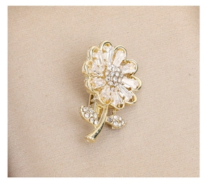 Detailed macro view of golden floral brooch with rectangular zircon and crystals on silk
