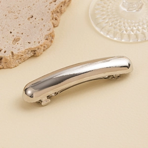 Close-up of a sleek silver metal hair clip featuring a polished curved mirror finish