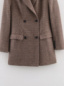Detailed close-up of brown houndstooth blazer fabric and classic double-breasted buttons