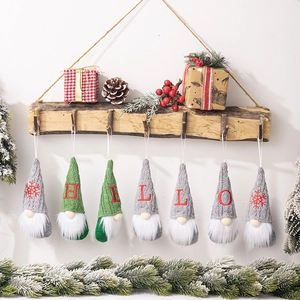 Detail of knitted Christmas gnomes with embroidered HELLO letters on wooden branch