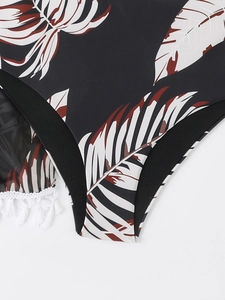 Gros plan du bas de bikini à imprimé tropical avec bordure noire et détail de gland