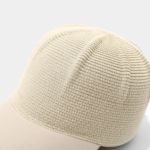 Detailed close-up of straw woven texture and cotton brim on a beige sun visor hat