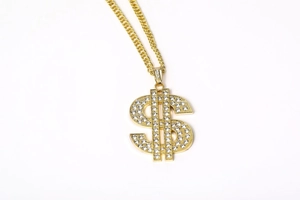 Macro view of gold iced-out dollar sign pendant with sparkling rhinestones on Cuban link chain