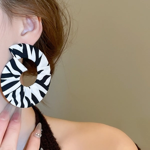Detail of round fabric earrings with zebra stripes shown on a side-view model profile