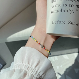 Close-up of rainbow beaded bracelet with a silver smiley face charm on a model's wrist
