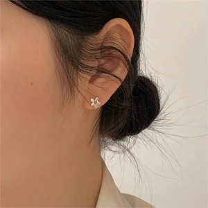 Close-up of minimalist 925 silver flower stud earring worn by a model in warm light