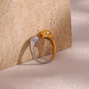 Detail shot of two-tone gold and silver open ring on a textured beige stone background