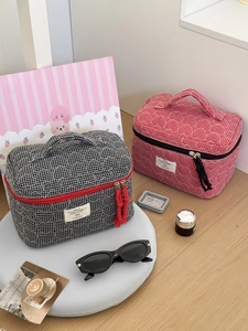 Close-up of quilted cotton cosmetic bag featuring checkered pattern and tassel zipper