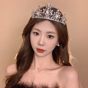 Close-up of a bridal tiara set with crystal flowers and matching pearl jewelry on model
