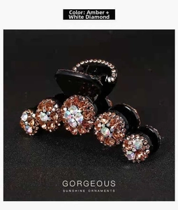 Dettaglio di un fermaglio nero con motivi floreali in strass color ambra e bianco