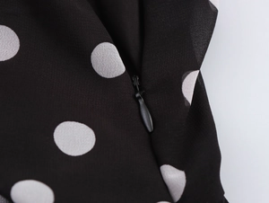 Détail de la fermeture éclair invisible sur une robe à pois noirs de style français
