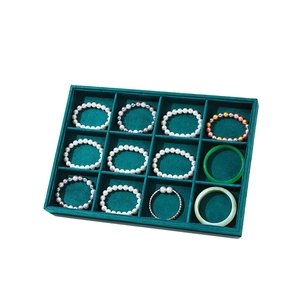 Emerald green velvet 12-slot jewelry tray showcasing pearl bracelets and jade bangles