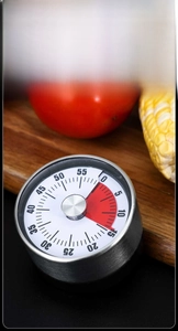 Mechanical kitchen timer with red time indicator and magnetic back on wooden board