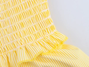Détail du tissu à rayures jaunes et blanches avec smocks et bordure à volants