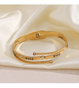 Detailed macro of gold-plated layered LOVE bracelet with zircons on silk background