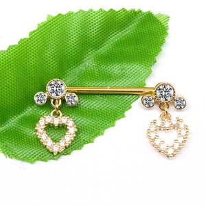 Golden heart pendant nipple rings with white zircon stones on a green leaf
