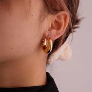 Close-up of chunky gold hoop earrings worn by model showing polished metal texture
