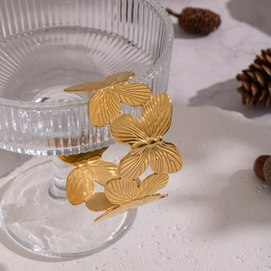 Detail of gold butterfly cuff bracelet with textured wings on a stylish glass display