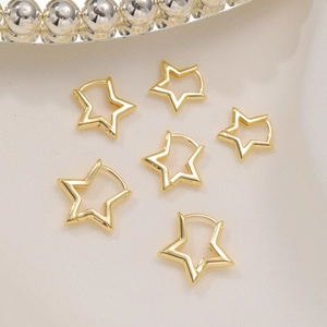 Flat lay of three pairs of golden star-shaped hoop earrings on soft beige fabric background