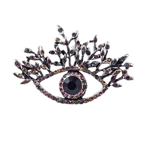 Artistic silver evil eye brooch with purple rhinestones and branch details on white background