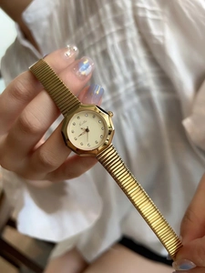 Detailed view of women's gold watch with stainless steel mesh band and rhinestone dial