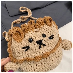Detail of handmade crocheted lion crossbody bag with beige yarn and brown mane accents
