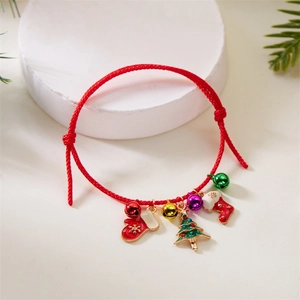 Close-up of red braided Christmas bracelet with bells, stocking, and tree pendants