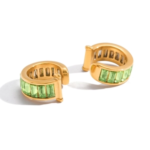 Détail macro de boucles d'oreilles plaquées or 18k avec zircons verts coupe baguette
