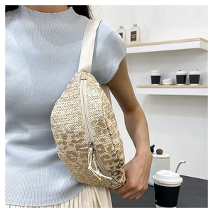 Detail of hand-woven straw belt bag with adjustable strap worn by a female model