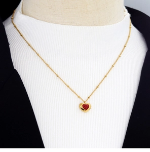 Close-up of gold heart necklace with red agate pendant on a model with blazer