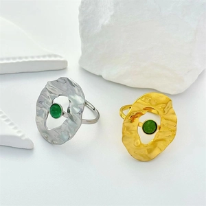 French vintage stainless steel rings in gold and silver with green gemstones on white props