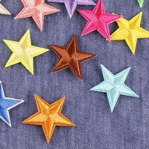 Colorful embroidered star patches scattered on denim fabric for clothing decoration