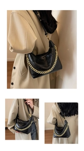 Detail of black quilted hobo bag with chunky gold chain strap and leather shoulder strap