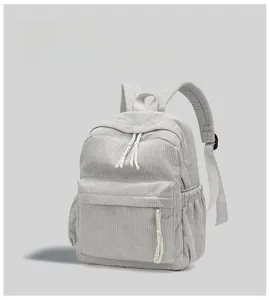 Detail of gray corduroy backpack showing textured fabric, front zipper pocket and side pockets