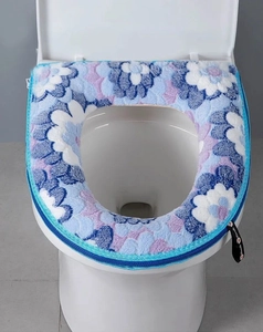 Detail of blue floral plush toilet seat cover with zipper closure on a white seat