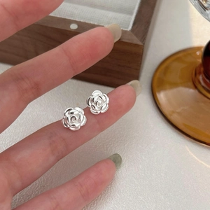 Detailed close-up of a silver floral stud earring with delicate layered petals