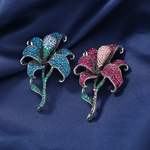 Detail of blue and pink lily brooches with sparkling crystals on dark silk fabric
