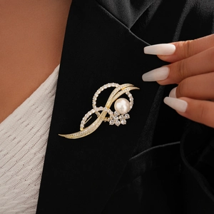 Close-up of a 14k gold plated twisted brooch with large pearl and sparkling zircons