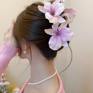 Detail of elegant pink acrylic flower hair clip worn on long brown hair in Chinese style