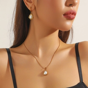 Close-up of gold-plated necklace and earrings set featuring elegant pear-shaped pearls