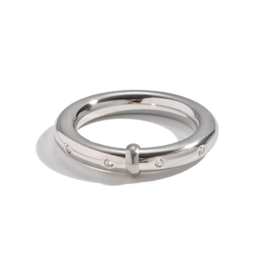 Vue macro de la bague en acier argenté avec quatre diamants ronds et design industriel
